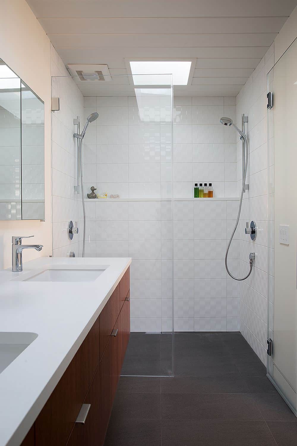 Bathroom is finished with textured white tiles while wooden vanity echoes the main theme