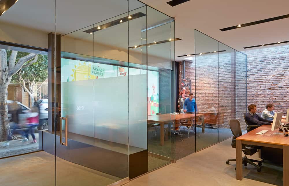 Behind a colorful graphic window there is a conference room divided from the lobby and the main room with entirely glass walls