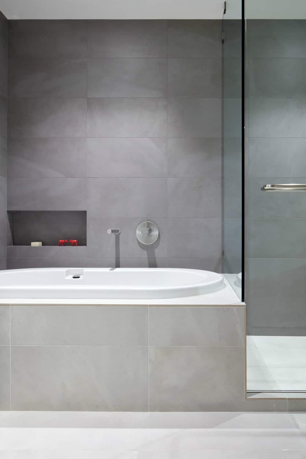 Modern minimalist bathroom features a bathtub and a glass shower stall