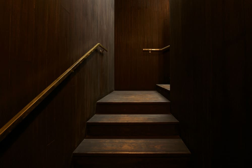 Wood-clad staircase with golden brass railing makes for luxurious feel