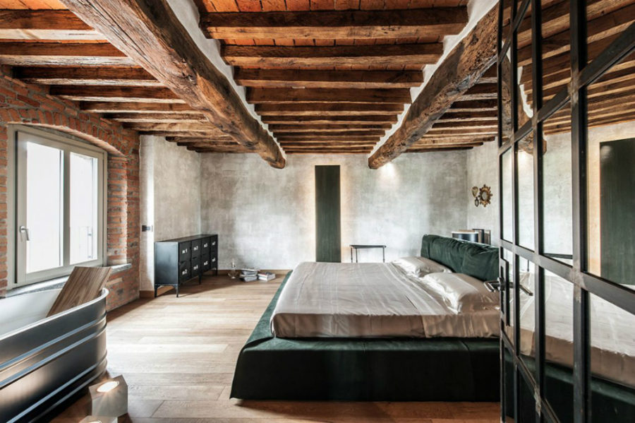 The giant bedroom has a huge soft bed frame and a metallic-shelled bathtub