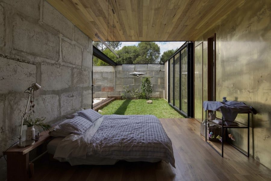 Part wooden, part brass bedroom with a concrete wall