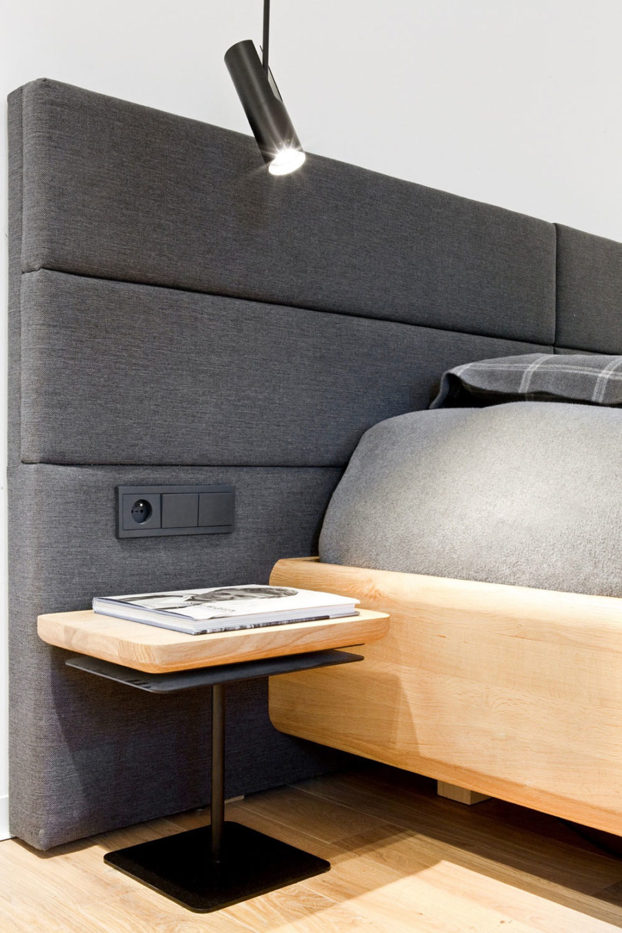 Soft upholstered headboard includes an electric outlet and light switches