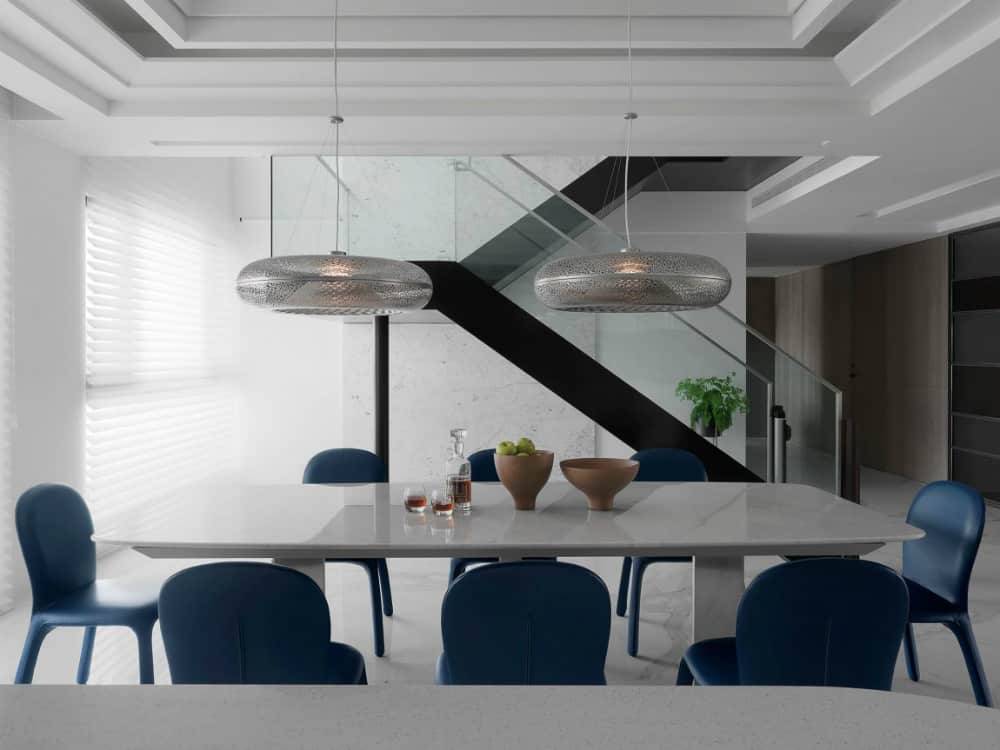 Two donut-shaped metallic pendants make a cool contrast with a marble table and leather chairs