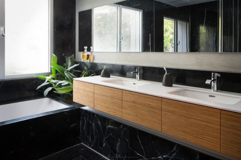 Bath clad entirely in black marble has an inbuilt planter flanking the tub