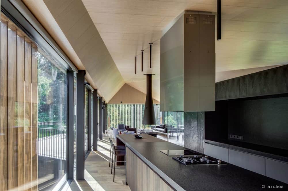 Black kitchen surfaces intermix with smooth minimalist wood