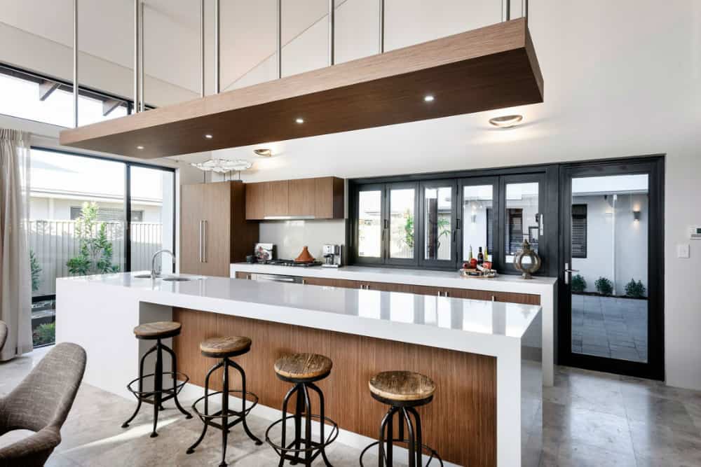 Modern kitchen in white and wood has plenty of daylight and views of backyard