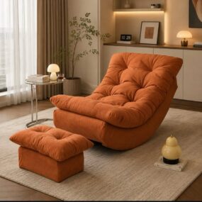 An oversized burnt orange tufted lounge chair with a matching ottoman on a cream rug, next to a glass side table with a mushroom lamp.