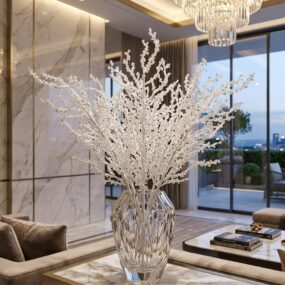 A cut-crystal faceted vase holding a tall spray of beaded white branches on a marble console, below a tiered crystal chandelier in a luxury living room.