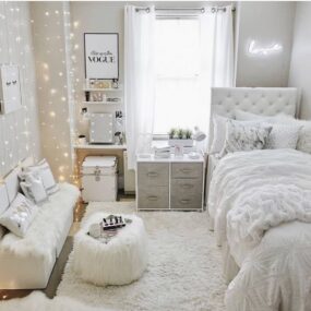 An all-white teen bedroom with a fairy-light curtain, pink “love” neon sign, tufted bed, vanity with lit mirror, and faux fur accents.