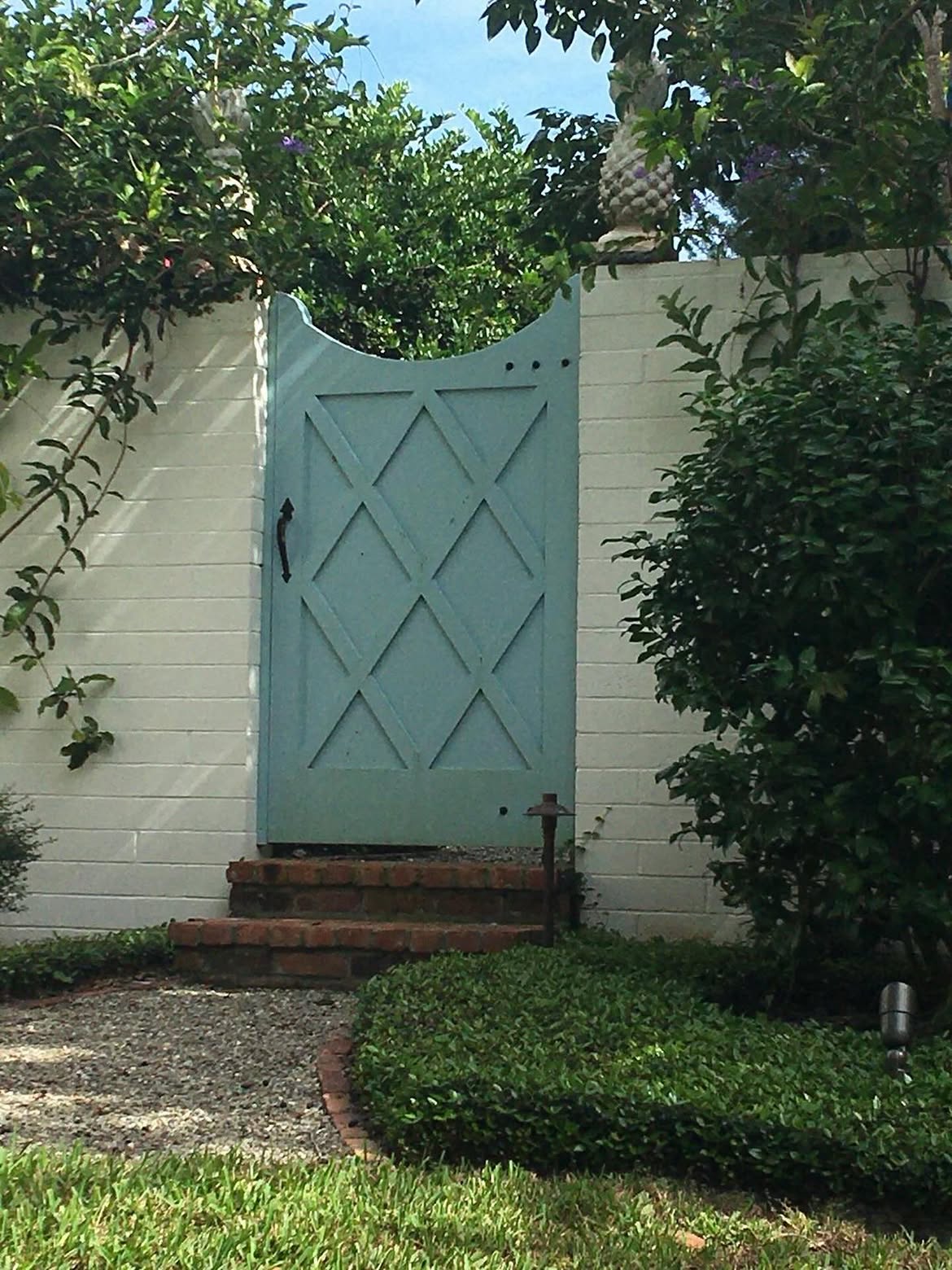 white-arched-gate-between-tall-hedges-lesliemaydesigns