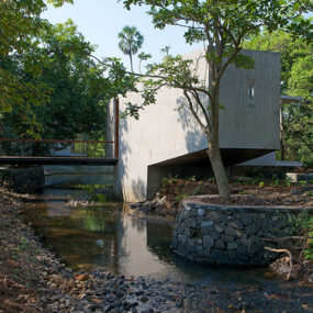 Steel Bridge over Stream Connects Private and Public Areas of Home