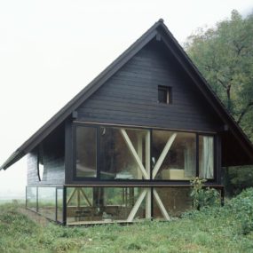 谷仓风格的住宅漂浮在较低的玻璃立面上的圆形窗户