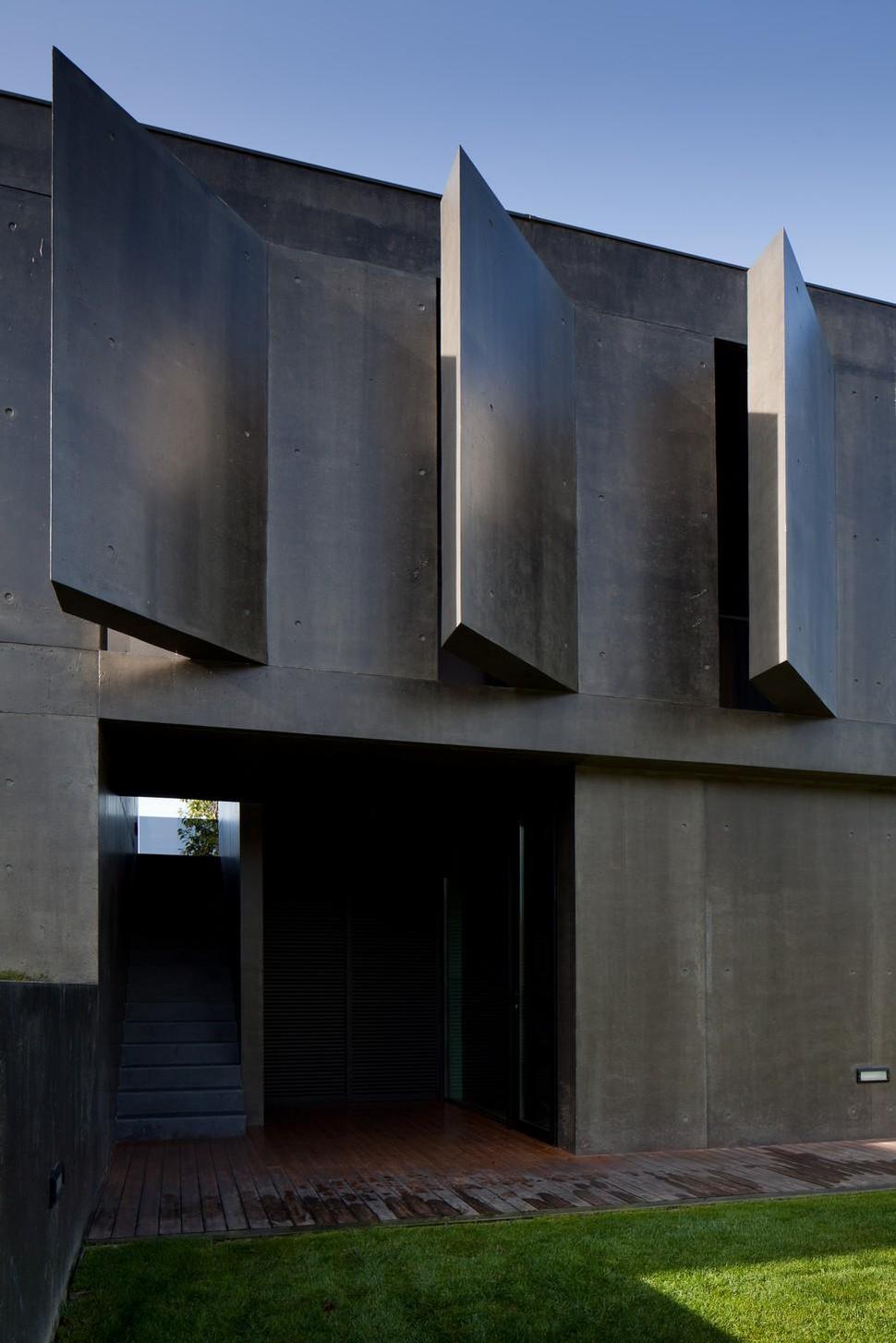 black-home-with-bright-interior-built-into-grassy-hillside-14-angled-concrete.jpg