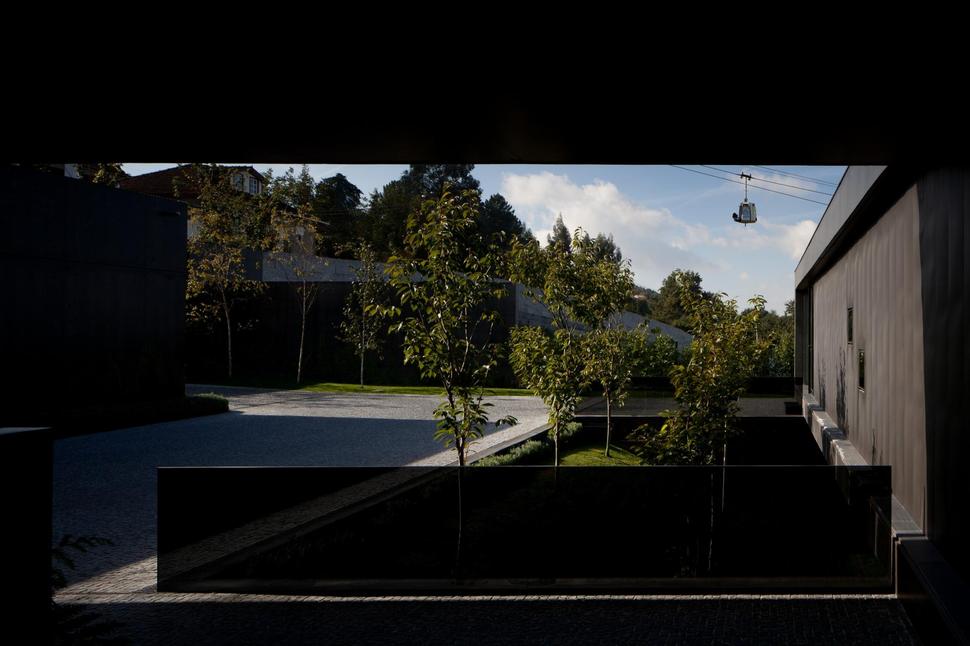 black-home-with-bright-interior-built-into-grassy-hillside-15-driveway.jpg