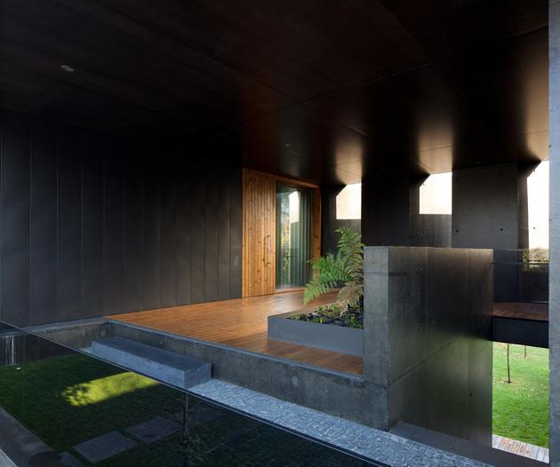 black-home-with-bright-interior-built-into-grassy-hillside-16-main-door.jpg