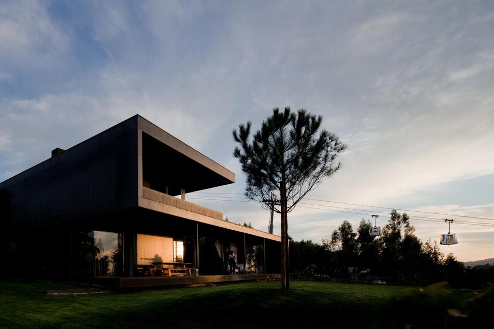 black-home-with-bright-interior-built-into-grassy-hillside-2-front-angle-shadows.jpg