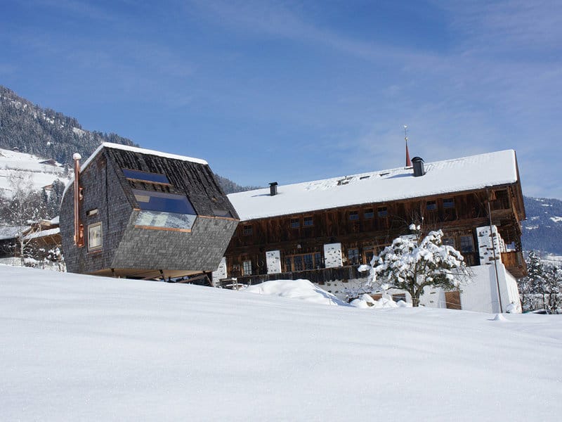 compact-irregularly-shaped-austrian-mountain-house-on-stilts-5-below-winter.jpg