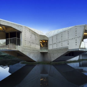 Futuristic concrete house with bridge access and eco appeal