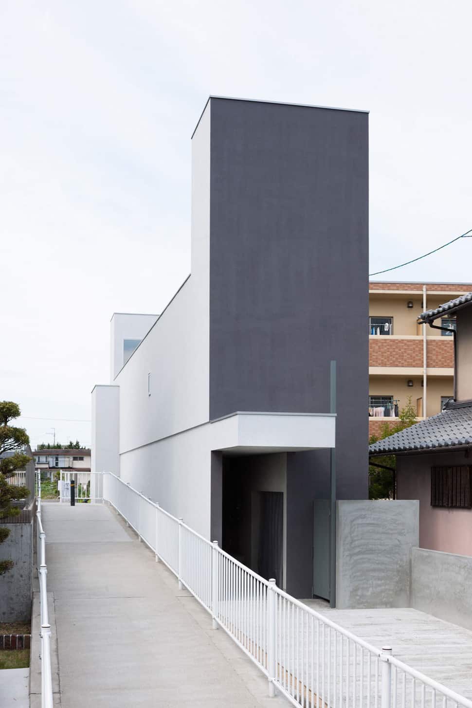 Narrow urban home with concrete walls and upper bridge