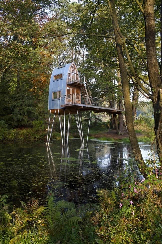 unusual forest cabin on stilts over pond 2 far angle